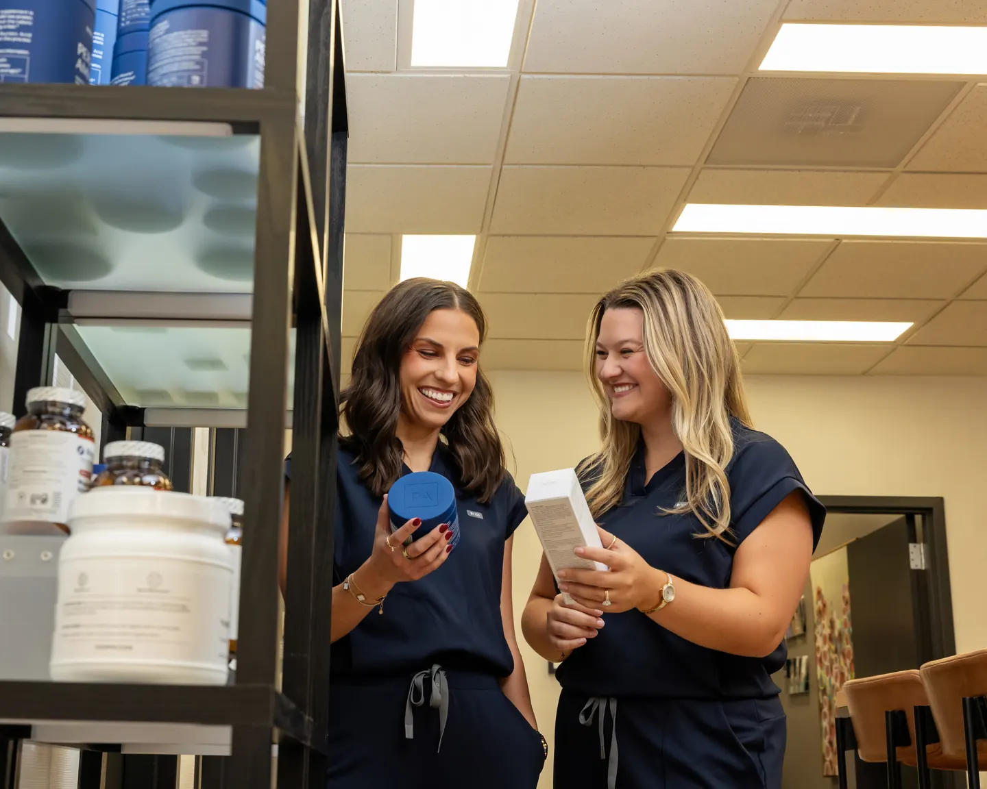 Two Premier Aesthetics team members comparing protein and supplement products